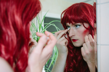 Non binary guy in drag wearing green dress and red wig