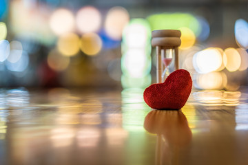 Heart model and hourglass on the wooden table, valentine day, love and time concepts.