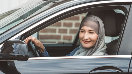 Muslim woman driving black luxury car