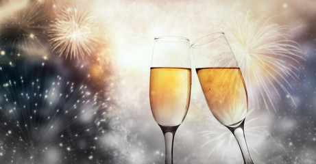 two champagne glasses ready to bring in the New Year - holiday lights and fireworks in the background