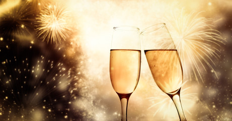 two champagne glasses ready to bring in the New Year - holiday lights and fireworks in the background