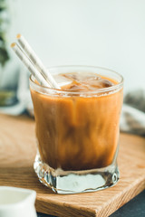 Refreshing iced latte in a glass with straws in a modern kitchen.
