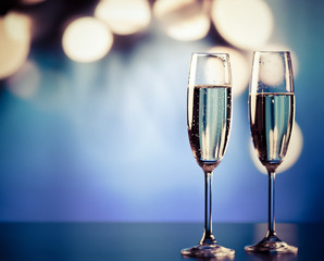two champagne glasses against holiday lights and fireworks - new year celebration