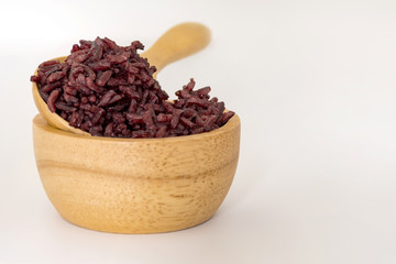 Wooden bowl and spoon with brown rice ready to eat on selective focus. Deep Purple rice, Homnil rice.