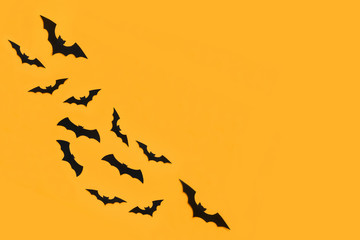 Halloween and decoration concept. Black paper bats flying over orange background. Halloween background.