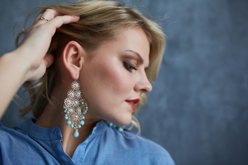 Blond girl in blue clothes with makeup and beautiful earring