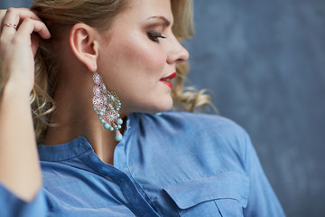 Blond girl in blue clothes with makeup and beautiful earring