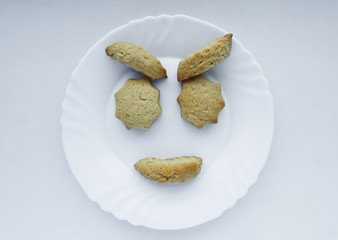 Cookies on a plate in the form of faces. Facial expression - joy, satisfaction