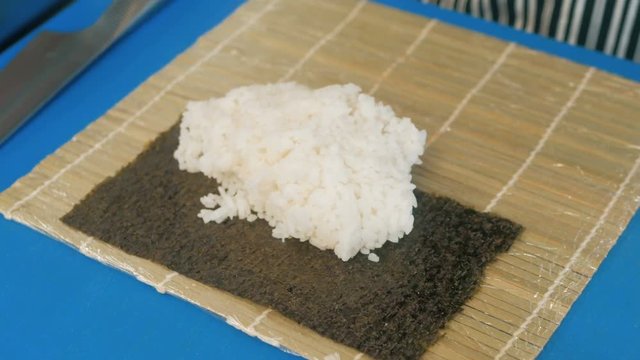 Close-up of professional chef's hands in black gloves making sushi and rolls in a restaurant kitchen. Japanese traditional food. Preparation process. step by step