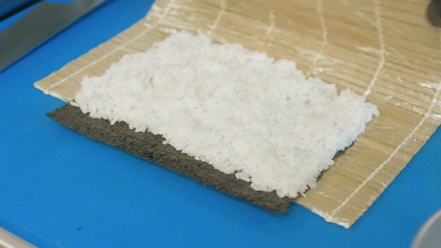 Close-up of professional chef's hands in black gloves making sushi and rolls in a restaurant kitchen. Japanese traditional food. Preparation process. step by step