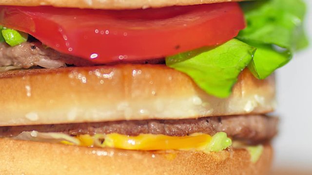 Extreme close-up rotating shot appetizing burger with grilled beef cutlet tomato cheese and lettuce