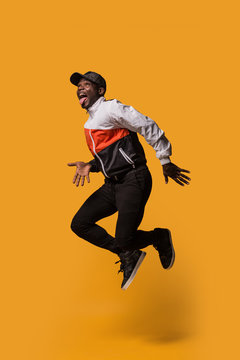 Stylish sporty man jumping over a yellow background
