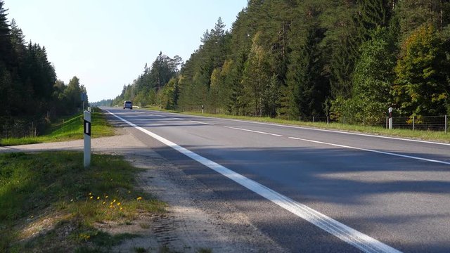 Two Passenger Cars Are Driving Away From Camera On The Forest Road In European Country