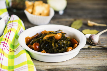 salad of seaweed and pickled mushrooms in a plate on a wooden board