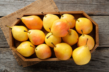 Fresh pears  in a box on wooden table.  top view.