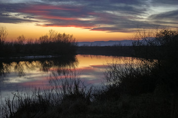 Fototapeta premium Colorful sunset with reflections in calm water of river Mures in Transylvania, Romania
