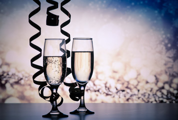 two champagne glasses with ribbons against holiday lights and fireworks - New Year celebrations