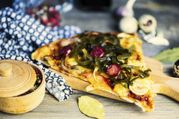 slice of pizza with sausage and seaweed, cheese on a wooden background