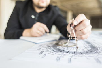 Naklejka premium architect builder works at the table with drawings. Helmet, drawings, compasses in the workplace