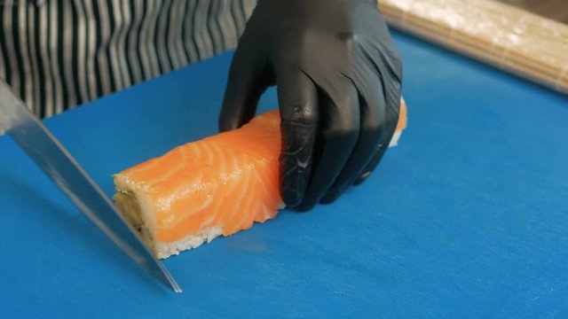 Close-up of professional chef's hands in black gloves making sushi and rolls in a restaurant kitchen. Japanese traditional food. Preparation process. step by step