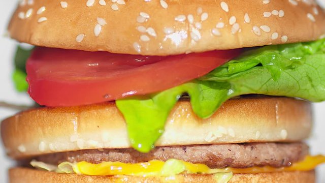 Extreme close-up piece of bread falling on finished appetizing burger