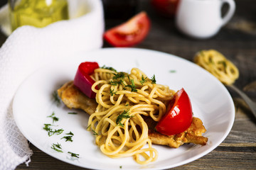 pasta and fried meat with spices and vegetables on a wooden board
