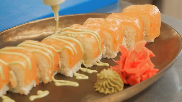 Close-up of professional chef's hands in black gloves making sushi and rolls in a restaurant kitchen. Japanese traditional food. Preparation process. step by step