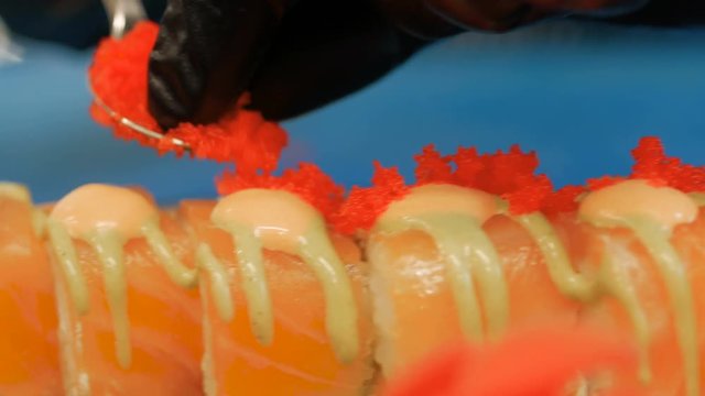 Close-up of professional chef's hands in black gloves making sushi and rolls in a restaurant kitchen. Japanese traditional food. Preparation process. step by step