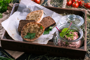 Appetizer of liver pate with toasted bread slices on wooden background