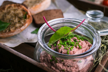 Appetizer of liver pate with toasted bread slices on wooden background