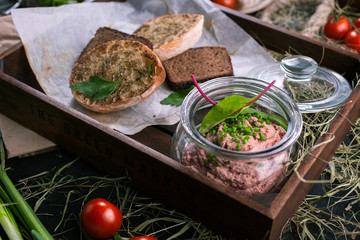 Appetizer of liver pate with toasted bread slices on wooden background