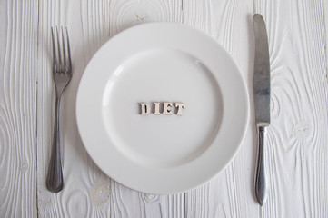 Words on white empty plate from wooden letters: Diet, anorexia and hunger concept. 