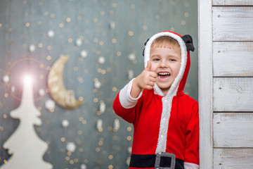 Happy child boy in santa costume showing thumb up