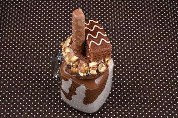 Chocolate extreme milkshake with brownie cake, chocolate paste and sweets. Crazy freakshake food trend. Copy space