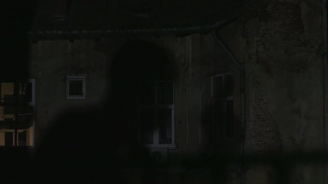 Shadow of man with gun reflecting on house. Dangerous killer trying to get into house. Lifestyle. Night time. Darkness.