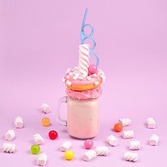 Pink strawberry freakshake with marshmallow and sweets.