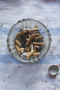 Close up of dirty ashtray with cigarettes and matches