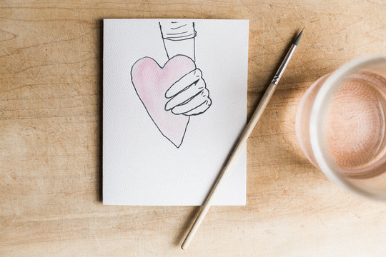 illustrated hand holding a watercolored heart