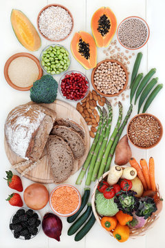 Healthy high fibre food concept with fruit, vegetables, whole grain rye bread, legumes, grains and cereal on rustic white wood background. High in antioxidants, anthocyanins, vitamins and minerals.