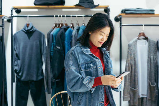 Business owner using smartphone in clothing store