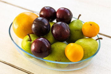 Fresh fruit in a bowl lying on a wooden table from a side view