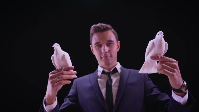 Magician with pigeons. Shows focus with two white pigeons. Magician releases dove from hands, slow motion
