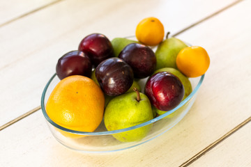 Fresh fruit in a bowl lying on a wooden table from a side view