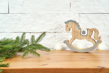 Christmas decoration with twigs of spruce and wooden horse on the old shelf on the background of a white brick wall