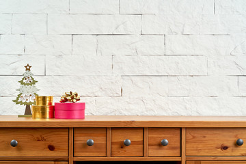 Christmas decoration with a gift on an old shelf on the background of a white brick wall