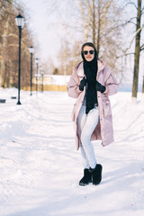 Fototapeta na wymiar Young stylish woman walking at the park on a sunny winter day. Winter Weekend Recreation.