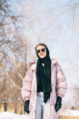 Portrait of Young stylish woman walking at the park on a sunny winter day. Winter Weekend Recreation.