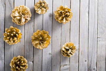 golden pine cones Christmas decoration on old rustic wooden table background