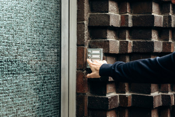 Close-up. The man rings the doorbell at the intercom.