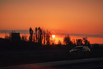 Fototapeta na wymiar Driving in a urban road in the city at colorful orange sunrise morning